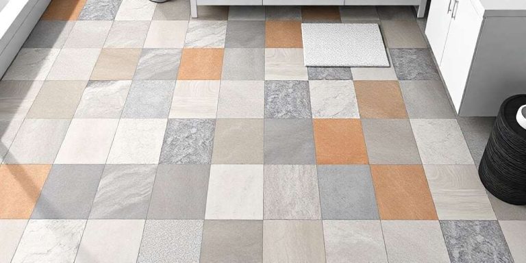 A tiled floor with a checkerboard pattern of beige, gray, white, and orange tiles in a room with white cabinets and a black woven basket.