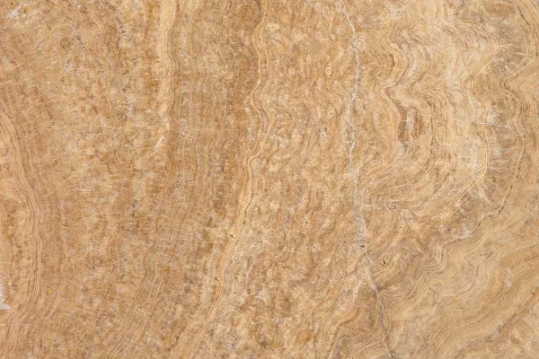 Close-up of a beige and light brown marble surface with natural wavy lines and subtle texture variations.